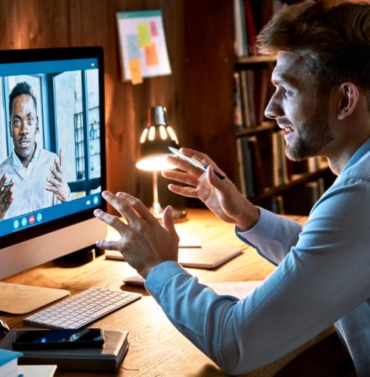 Caucasian business man talking with african male partner coach on video conference call discussing social distance work at virtual remote meeting videoconference chat using pc computer at home office.